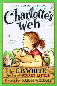 Book cover for Charlotte's Web showing a girl hugging a pig and spider dangling from the title.